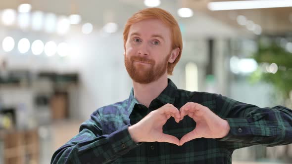 Portrait of Beard Redhead Man Making Heart Sign By Hand 