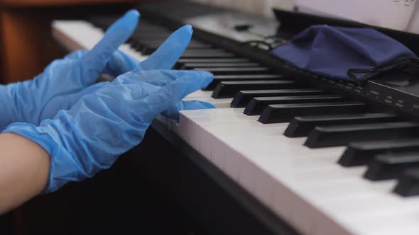 Electronic piano. Fingers press the piano keys. Hands in rubber gloves. Pandemic 2020