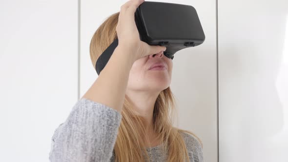 Female blond having 3D VR headset first time experience in living room 4K 2160p 30fps UltraHD footag