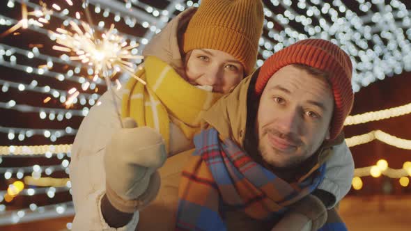 Portrait of Joyous Couple with Christmas Sparkler Outdoors