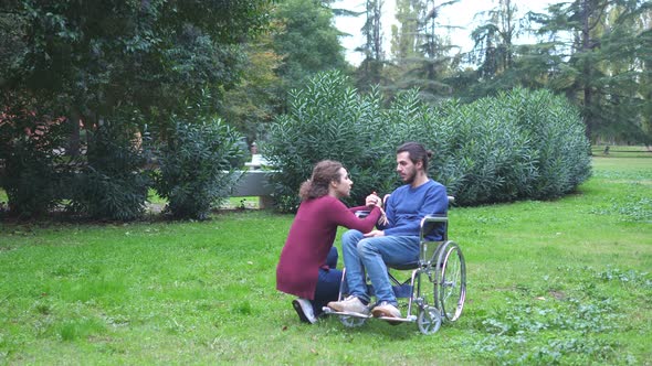 woman kneeling near her boyfriend using wheelchair comforts him