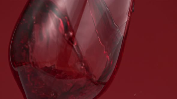Pouring Red Wine in Super Slow Motion on Red Background