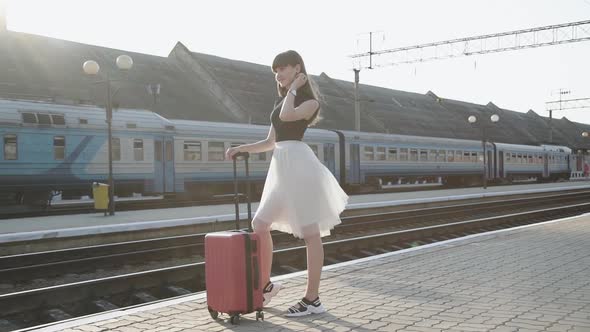 Elegant Lady Smiling and Poses with Lush Skirt at Suitcase on Railway Platform