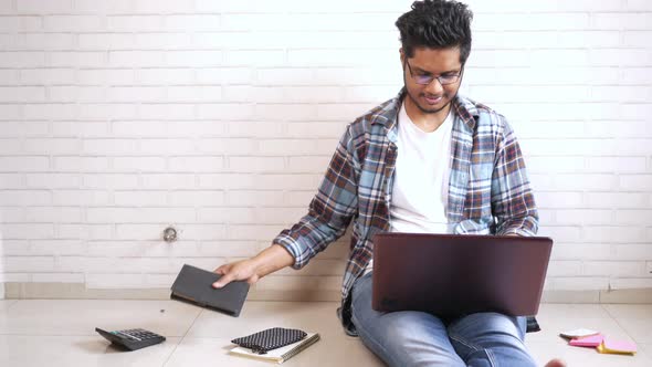 Young Man in Casual Dress Sitting on Floor Working on Laptop