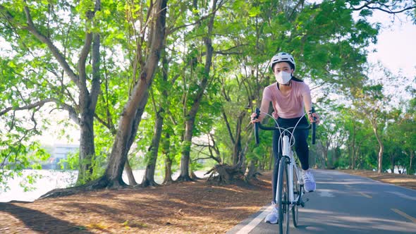 Asian young sport woman riding bicycle in the evening in public park.