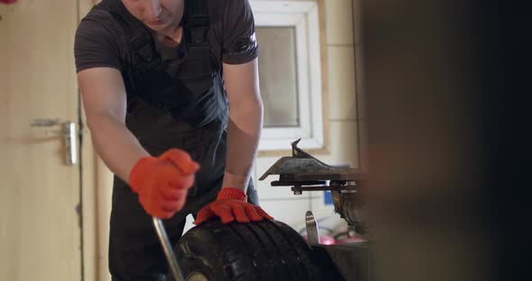 Mechanic Uses Wrench for Removing a Tire From an Alloy Wheel on a Tire Changer