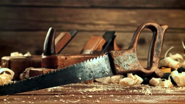 A Saw Falls on a Table with Sawdust