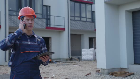 Employee Speaks on His Phone and Hold Tablet