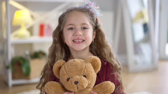 Closeup Portrait of Charming Little Girl Holding Teddy Bear Looking at Camera Smiling