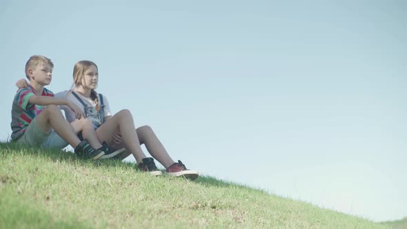 Children sitting together on hillside looking at view