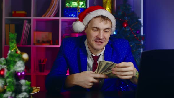 Happy Businessman in Santa Hat with Money in Office