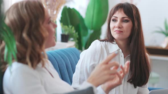 Two Pretty Women Sitting and Talking on Couch