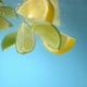Super slow motion shot of lemons and limes falling into the water with a splash. Blue background. - VideoHive Item for Sale