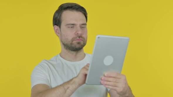 Young Man using Digital Tablet on Yellow Background