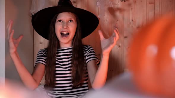 Little Pretty Girl Witch in Black Wizard Hat Says Boo with Scary Gesture