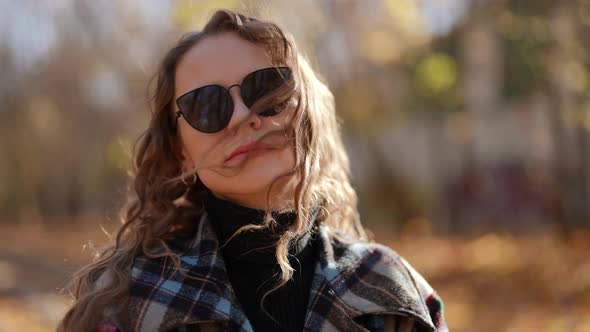 Portrait of a Woman in Dark Glasses and a Plaid Coat on a Sunny Day