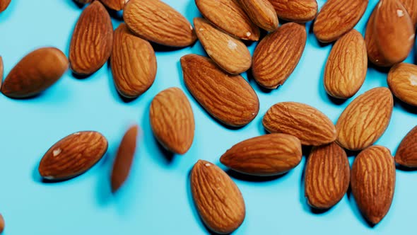 Almonds are falling down on a blue background. The appetizing portion of nuts.