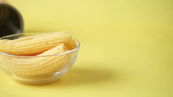 Baby Corn in a Bowl with a Empty Can Container on Yellow Background