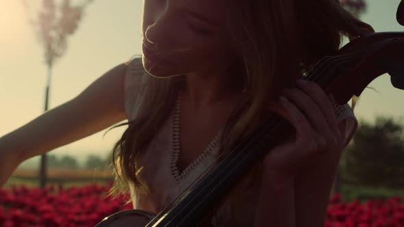 Closeup Inspired Young Woman Playing Cello in Blooming Summer Garden Outdoors