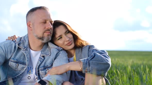 Loving Couple Resting Sitting in the Tall Green Grass in the Middle of the Field