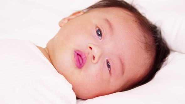 happy newborn baby lying on a white bed and blanket comfortable and safety