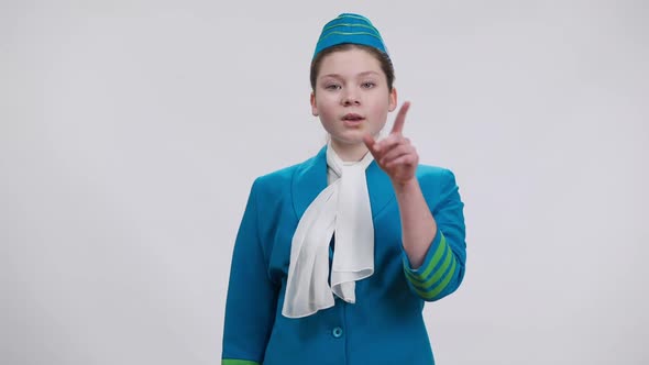 Serious Girl in Stewardess Uniform Putting Finger on Lips Showing Hush Gesture Looking at Camera