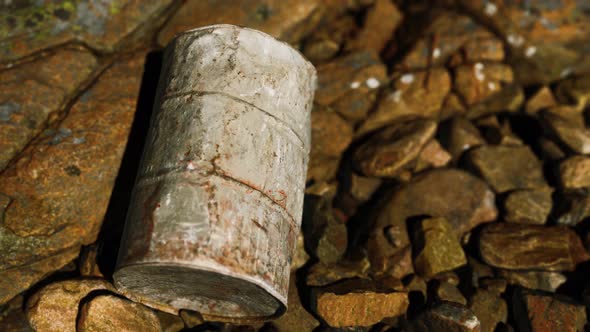 Rusty Destroyed Metal Barrel on Beach Rocks