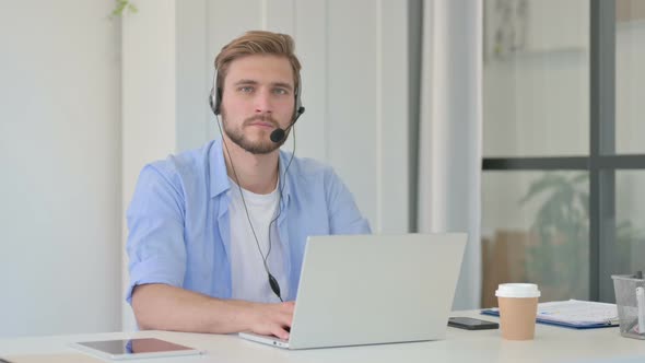 Creative Man with Headset and Laptop Looking at Camera
