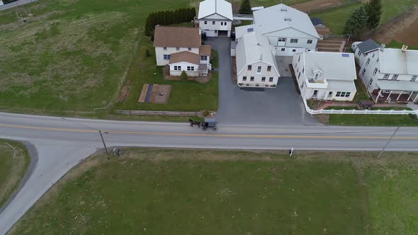 Amish Horse and Buggy Riding along Countryside Road Passing Amish Home