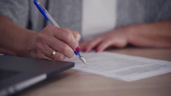 Woman Sitting Behind Wooden Table and Making Notes