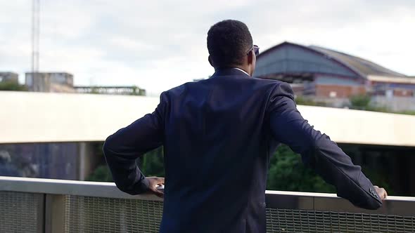 handsome businessman leans at the fence