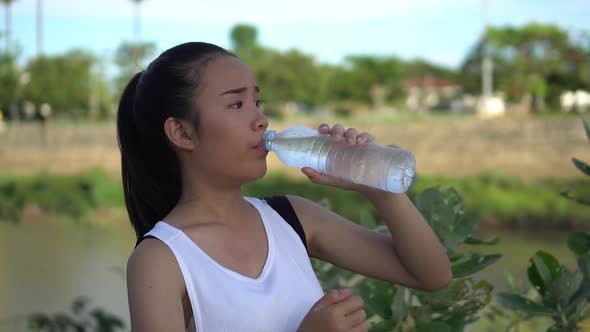 Young woman drinking water after exercise