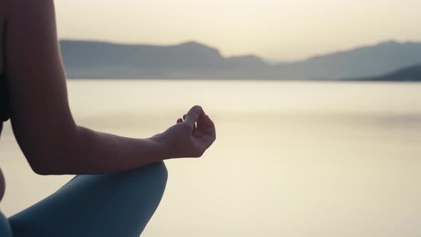 Closeup of the Hands of a Woman Meditating By the Ocean at Sunrise