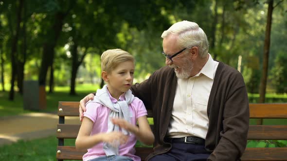 Cheerful Boy Tells Joke to Grandfather, Laughing Together, Having Fun Outdoors