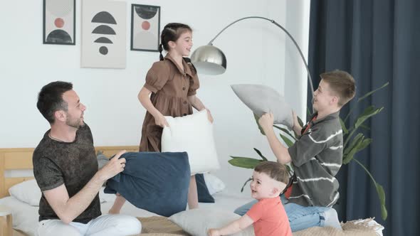 Playful Young Family Having Fun with Children They are Fighting Pillows in the Bedroom