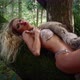 Woman in a Bikini and Scarf Made of Natural Fur Lies on a Tree and Sings a Song - VideoHive Item for Sale