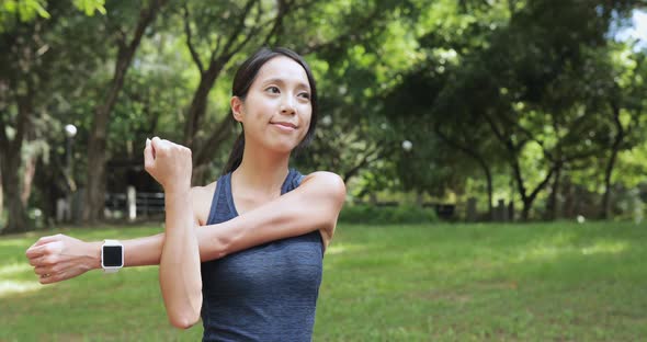 Sport woman stretching arm in park