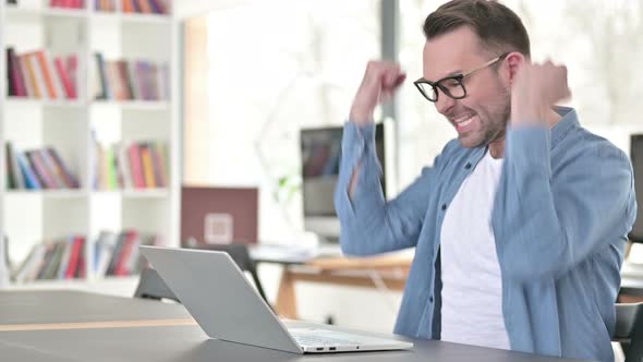 Young Man Celebrating Success on Laptop