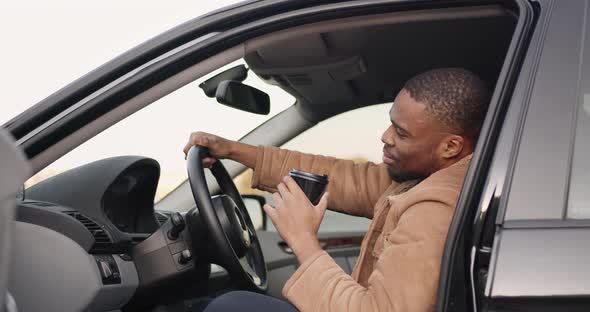 Black Driver Behind the Wheel with Coffee to Go