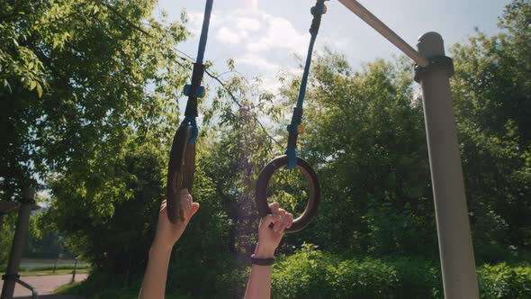 Closeup of Woman Hands Hanging and Swinging on Gymnastic Rings Back and Forth