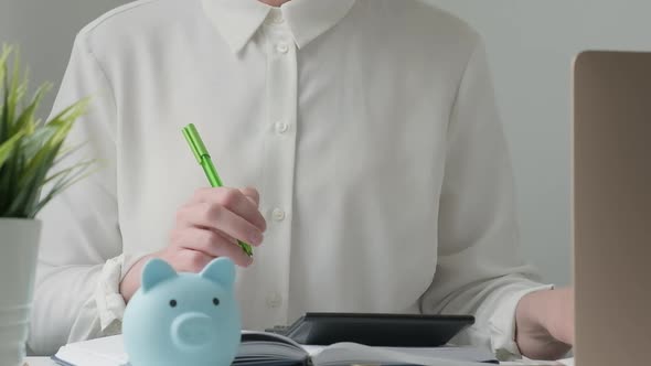 Woman Using Pen Writing on Bank Account Book While Holding the Bills to Calculate at Home Workplace