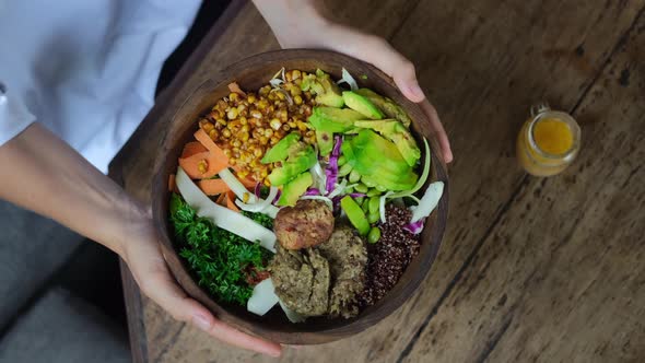 Top View of Female Hands Table Setting Holding Tasty Healthy Vegan Bowl with Tofu Quinoa and Avocado