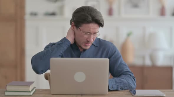 Young Man having Neck Pain while using Laptop in Office