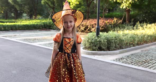 Cute Little Caucasian Girl with Blonde Hair Seven Years Old in Costume of Witch with Hat and Black