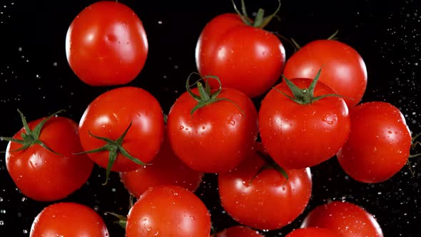 Super Slow Motion Shot of Flying Fresh Tomatoes and Water Side Splash Isolated on Black at 1000 Fps