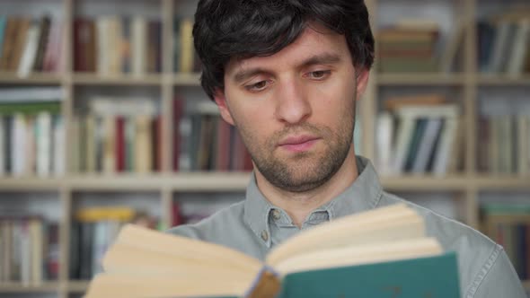 Young Male Student Reading a Book in a Library