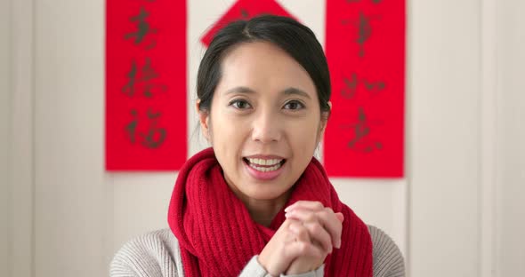 Chinese woman holding red packet and blessing for good fortune at homeNi un