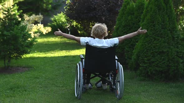 Elderly Caucasian Woman Doing Exercises While Sitting in a Wheelchair Outdoors