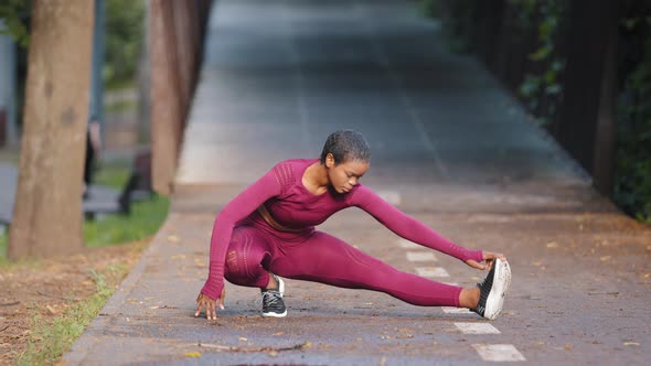 Portrait of African American Sporty Woman Doing Stretching Exercises in Park Before Training