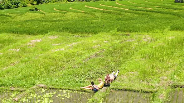 Overview clip of couple sunbathing among rice paddies and rice fields before panning off camera